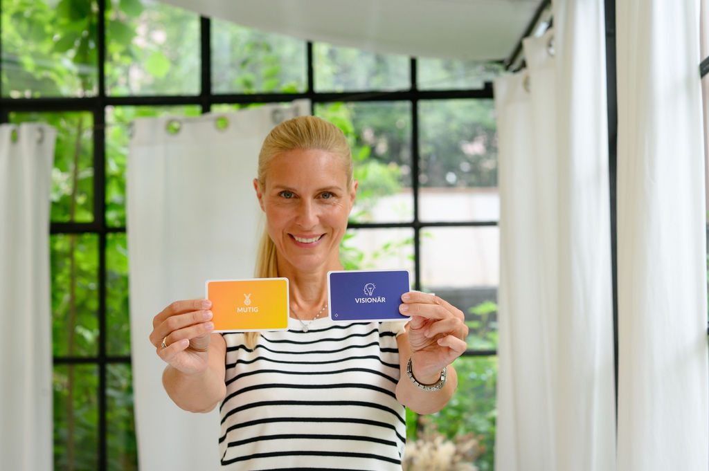 Kristina mit jeweils einer Karte in einer Hand